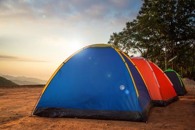Tent on landscape against sky at sunset
