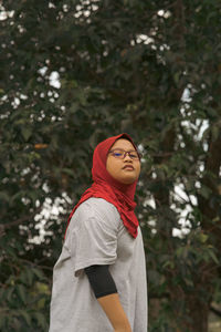 Portrait of young woman standing against plants