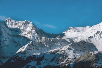 Scenic view of snowcapped mountains against blue sky