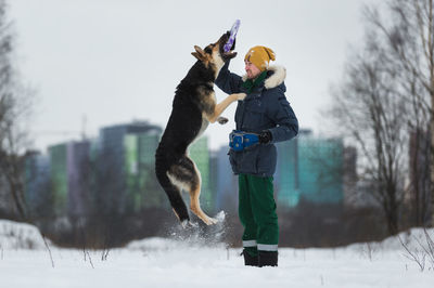 Man and dog playing with plastic ring during winter