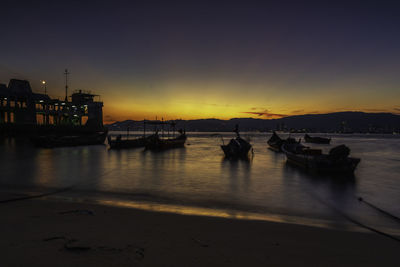 Silhouette boats in sea against sky at night