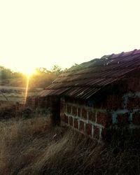 Abandoned structure on field at sunset