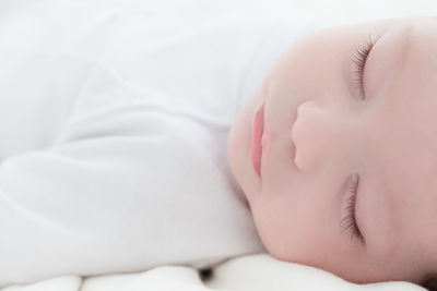 Close-up of baby sleeping on bed