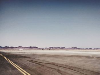 Scenic view of road by land against clear sky