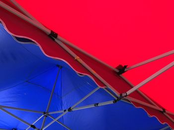 Low angle view of red umbrella against clear blue sky