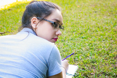 Rear view of young woman studying at park