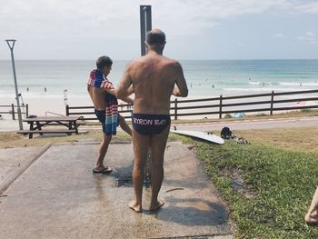 Rear view of shirtless man standing on beach