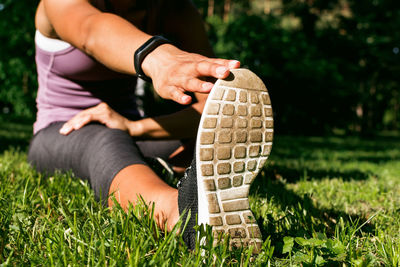 Low section of young woman exercising on grassy field at park