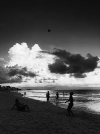 People playing on beach against sky