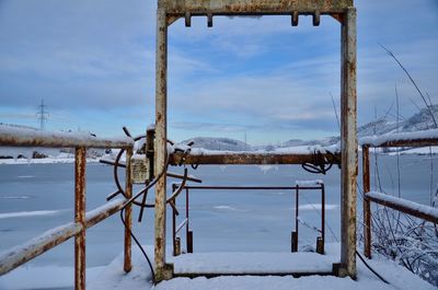 Snow covered landscape by lake against sky