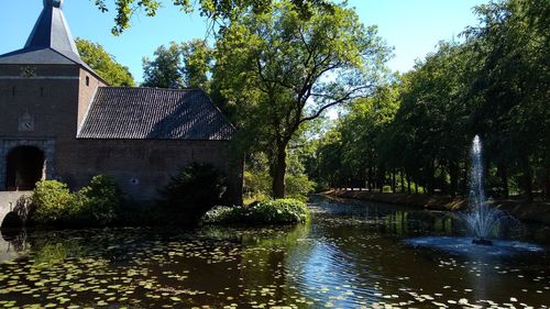 Lake and trees by building against sky