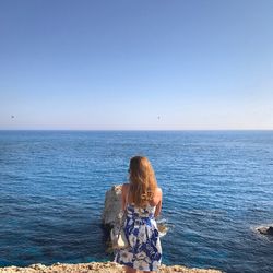 Rear view of woman in sea against clear sky