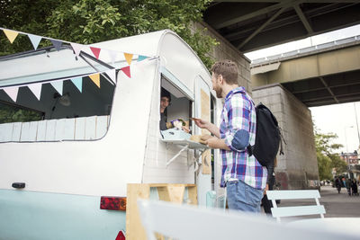 Side view of man buying food from owner in food truck