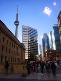 People on modern buildings in city against sky