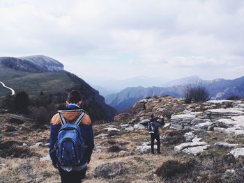 Rear view of people standing on rock against sky