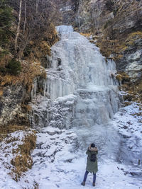 Rear view of woman standing on snow covered mountain