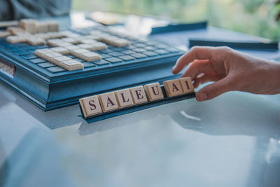 Cropped hand of man holding alphabet blocks on table