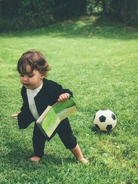 Full length of baby girl holding book while standing at park