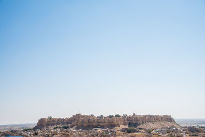 Buildings in city against clear blue sky