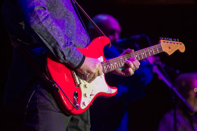 Midsection of man playing guitar
