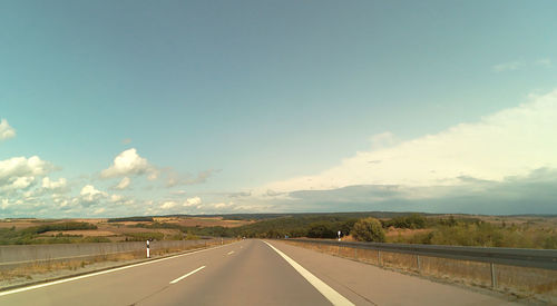 Road passing through landscape against sky