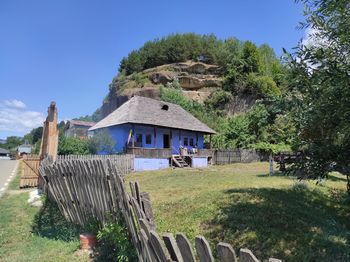 House on field by trees against blue sky