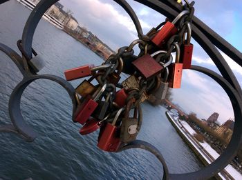 Close-up of padlocks hanging on railing against sky