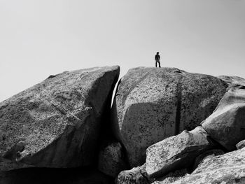 Low angle view of man standing on rock against sky