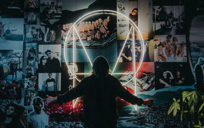 Rear view of people standing against illuminated wall