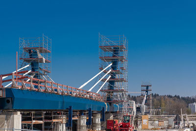 Low angle view of crane against clear blue sky