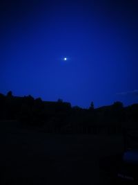 Silhouette landscape against clear blue sky at night