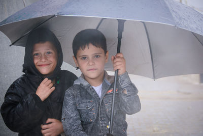 Little refugee children with umbrella in the rain, refugee with umbrella.