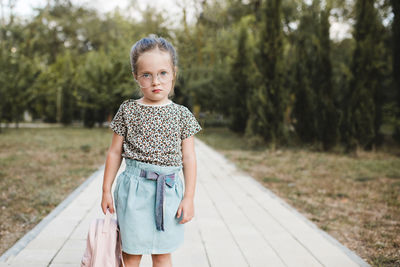 Funny cute child girl 4-5 year old wear glasses and casual clothes holding backpack