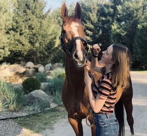 Girl with horse standing outdoors