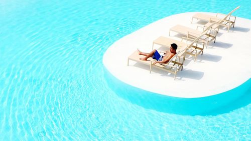 High angle view of shirtless man resting by swimming pool