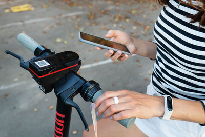 A girl rents an electric scooter with an application on her phone.