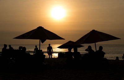 Silhouette people on beach against sky during sunset