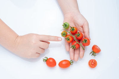 Cropped image of hand holding strawberry over white background