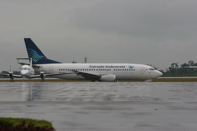 Airplane on airport runway against sky