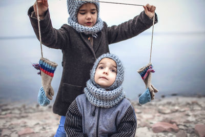 Girl in knitted grey hat sharing gloves with her frozen brother