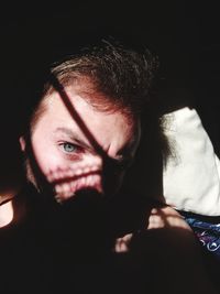 Close-up portrait of young man lying on bed at home