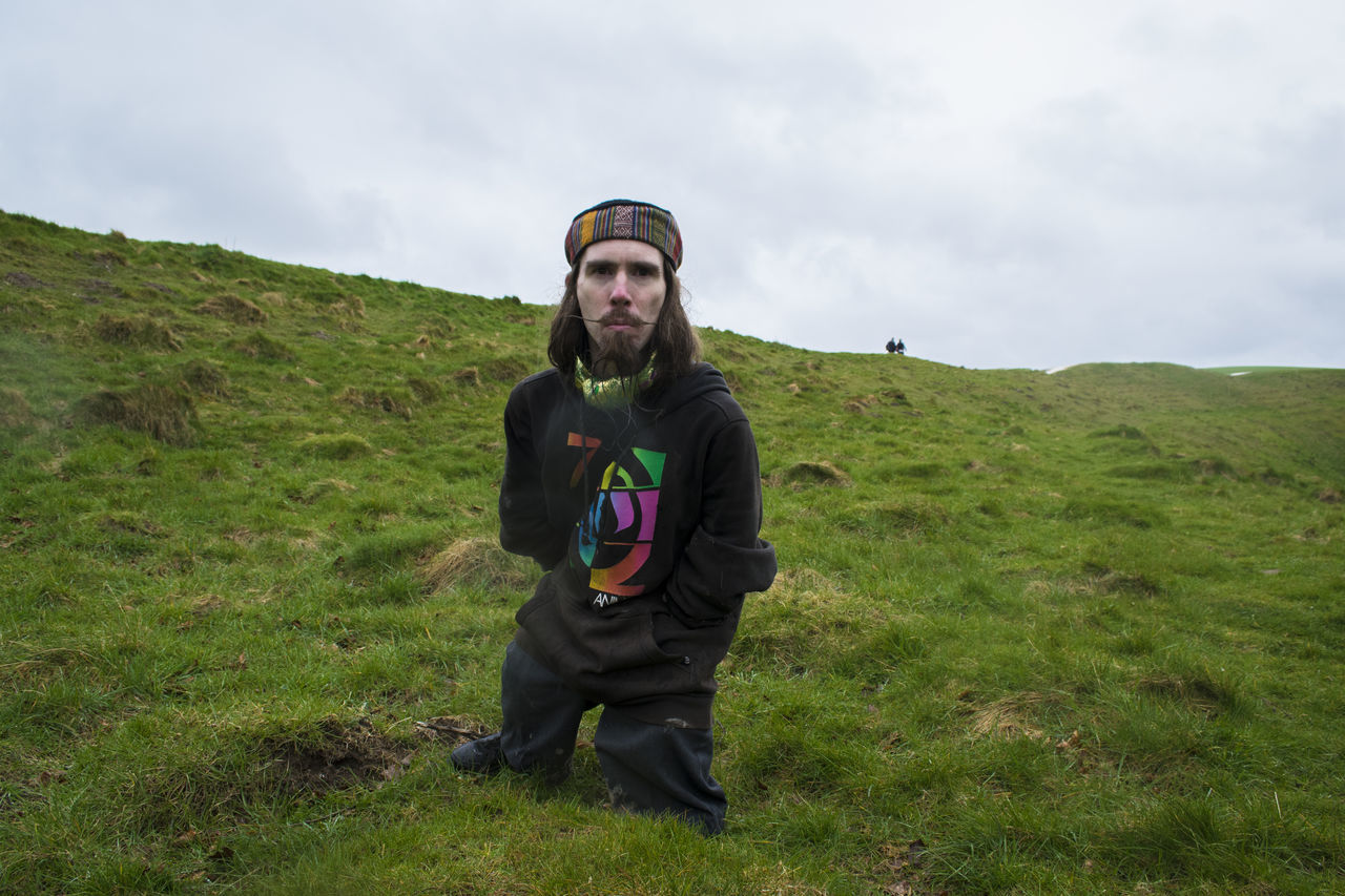 grass, casual clothing, looking at camera, person, portrait, lifestyles, young adult, leisure activity, full length, smiling, field, sky, front view, standing, grassy, young men, landscape, happiness