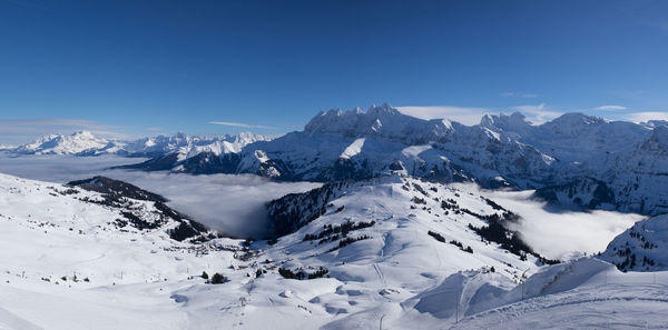 Scenic view of snowcapped mountains against blue sky