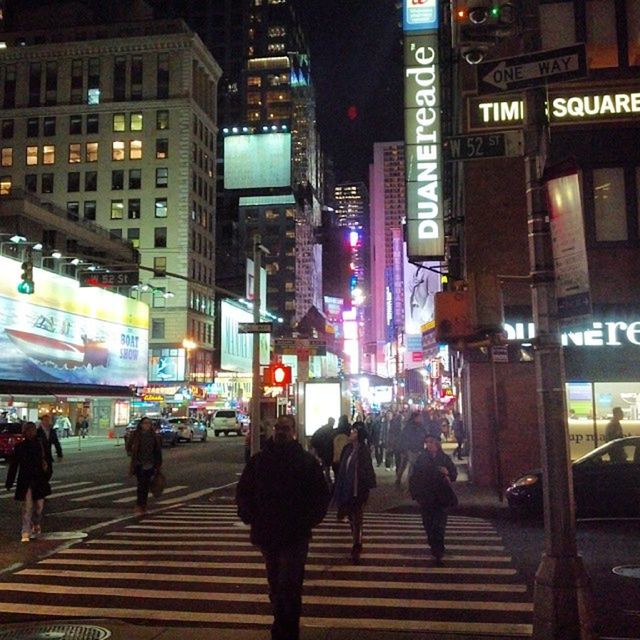 city, building exterior, architecture, illuminated, built structure, city life, night, transportation, street, large group of people, city street, walking, zebra crossing, men, person, on the move, road, lifestyles, traffic