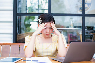 Young woman using mobile phone while sitting on table