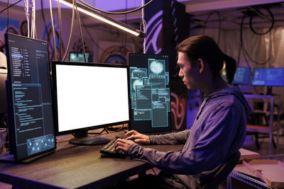 Rear view of man using laptop at office