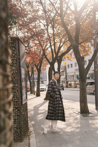 Woman standing on footpath amidst plants