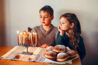 Cute sibling looking at burning candles on table