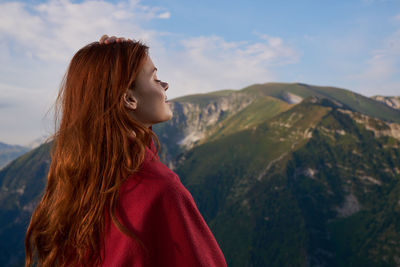 Rear view of woman looking at mountains against sky