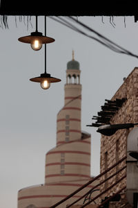 Low angle view of illuminated street light by building against sky